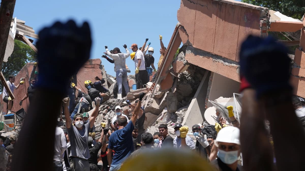 Rescatistas y voluntarios piden silencio sobre los escombros de un edificio derrumbado