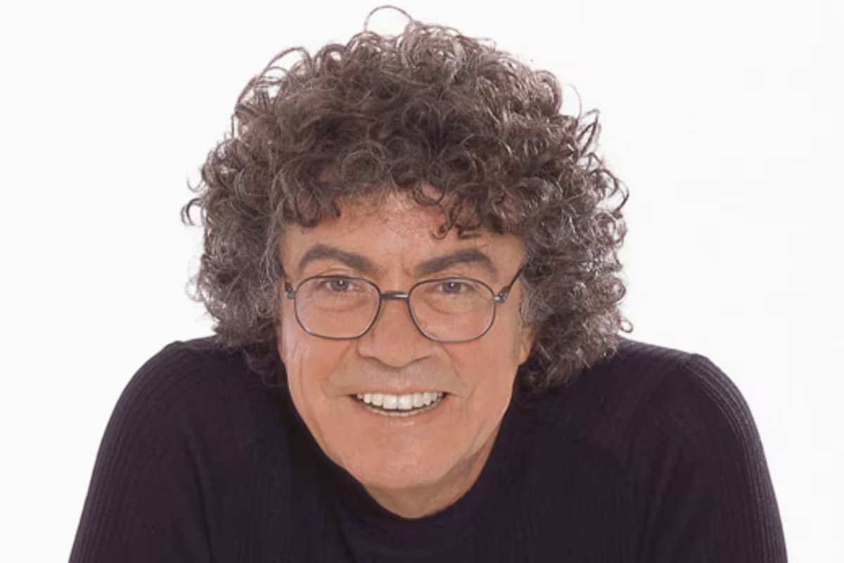 Retrato del cantautor Piero, sonriente, con gafas y cabello rizado canoso
