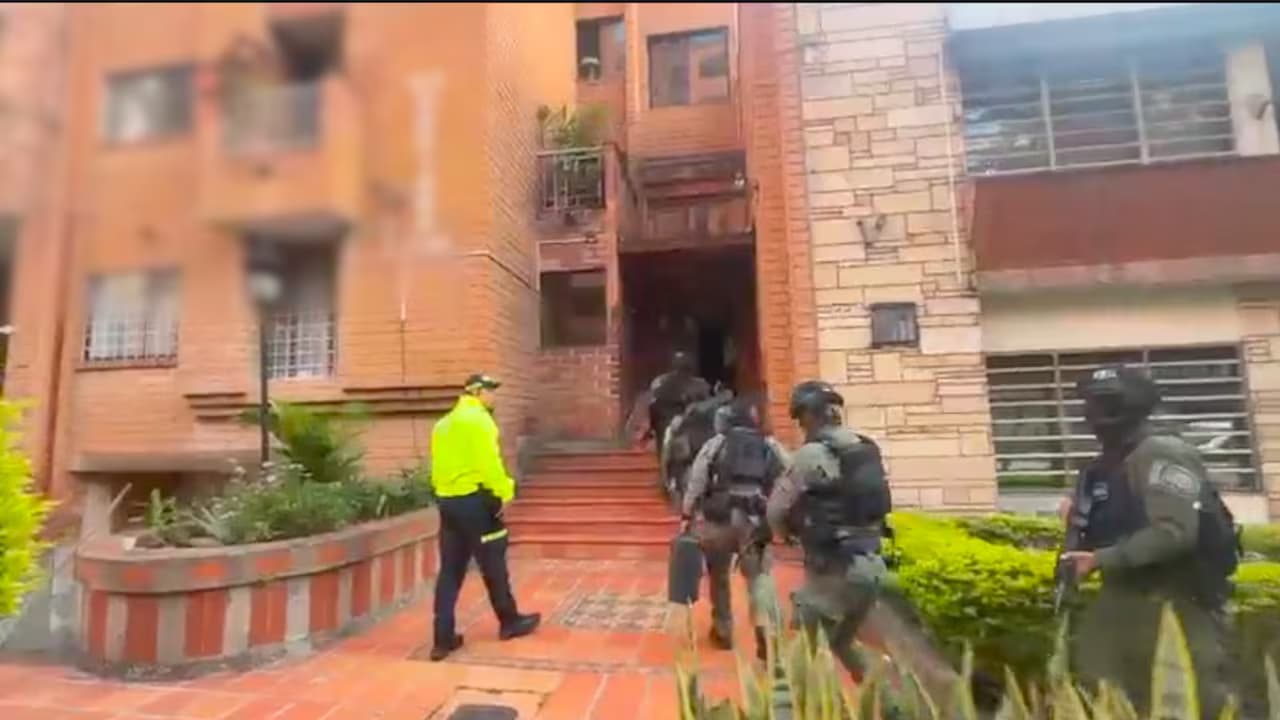 Uniformados de la Policía suben las escaleras de un edificio residencial durante un allanamiento