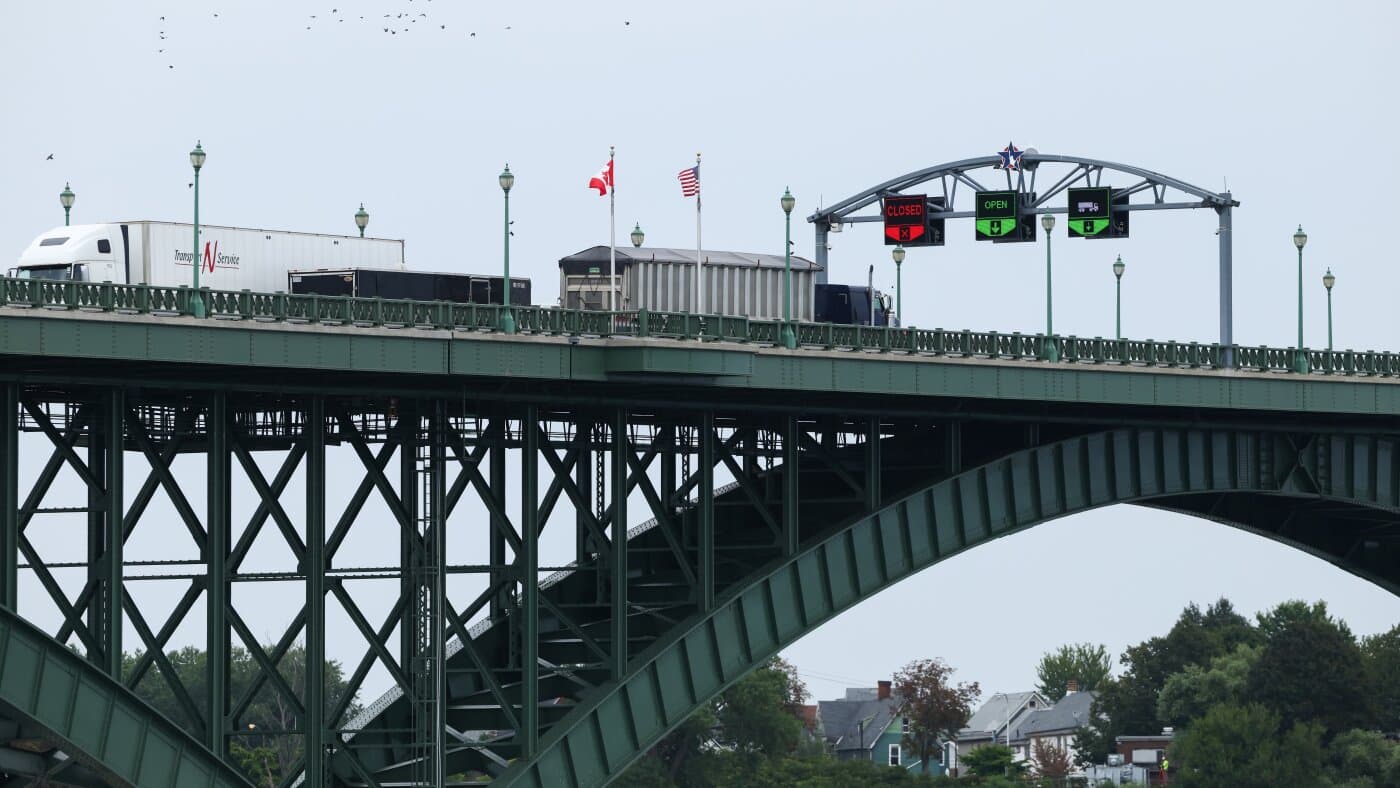 Camiones de carga cruzan el puente de la Paz entre Canadá y Estados Unidos, con las dos banderas al fondo