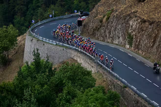 El pelotón de la Vuelta a España rueda por una carretera de montaña en curva cerrada
