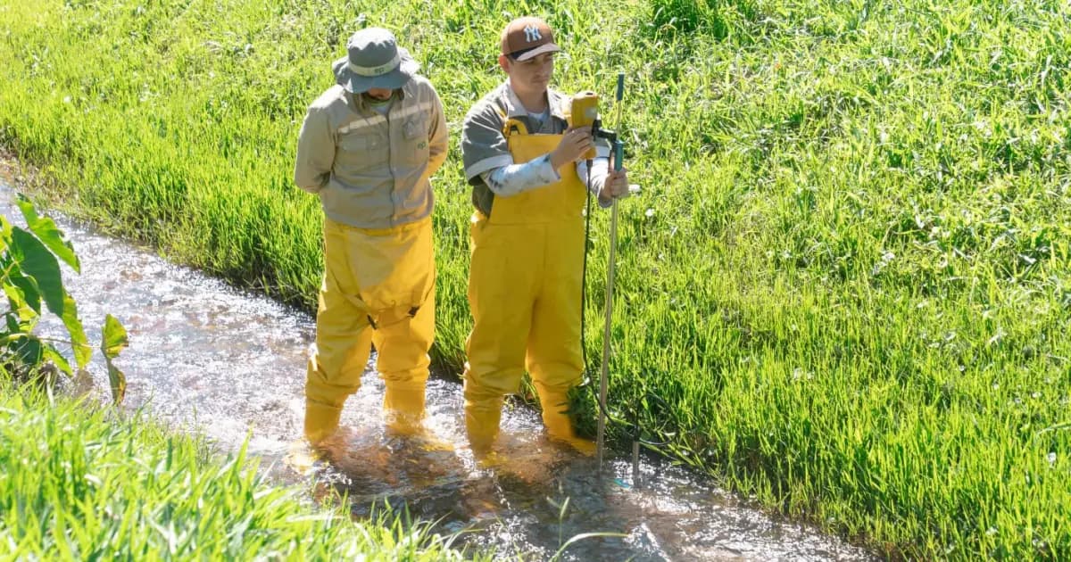 Dos técnicos de EPM miden el caudal de una quebrada en una zona rural