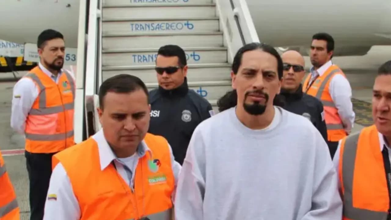 David Murcia Guzmán camina custodiado por funcionarios con chalecos naranjas junto a la escalerilla de un avión