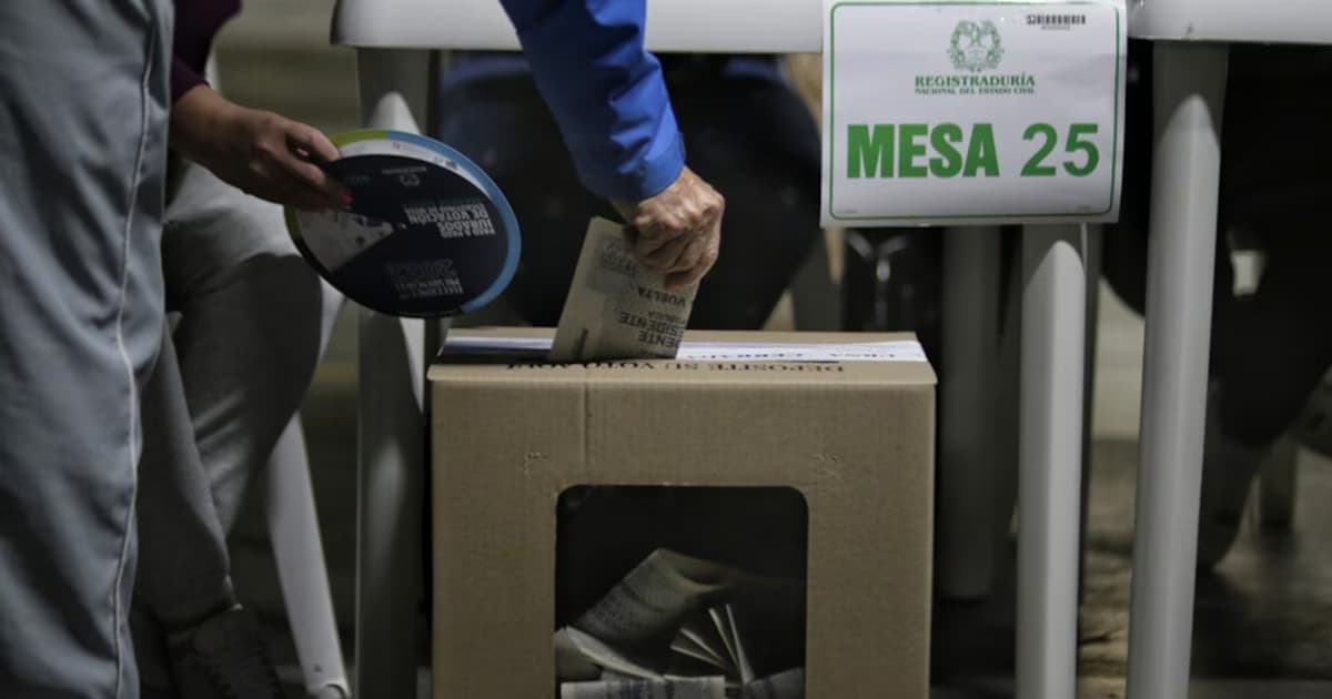 Un votante deposita su tarjetón en una urna de la Registraduría junto al letrero de la mesa 25
