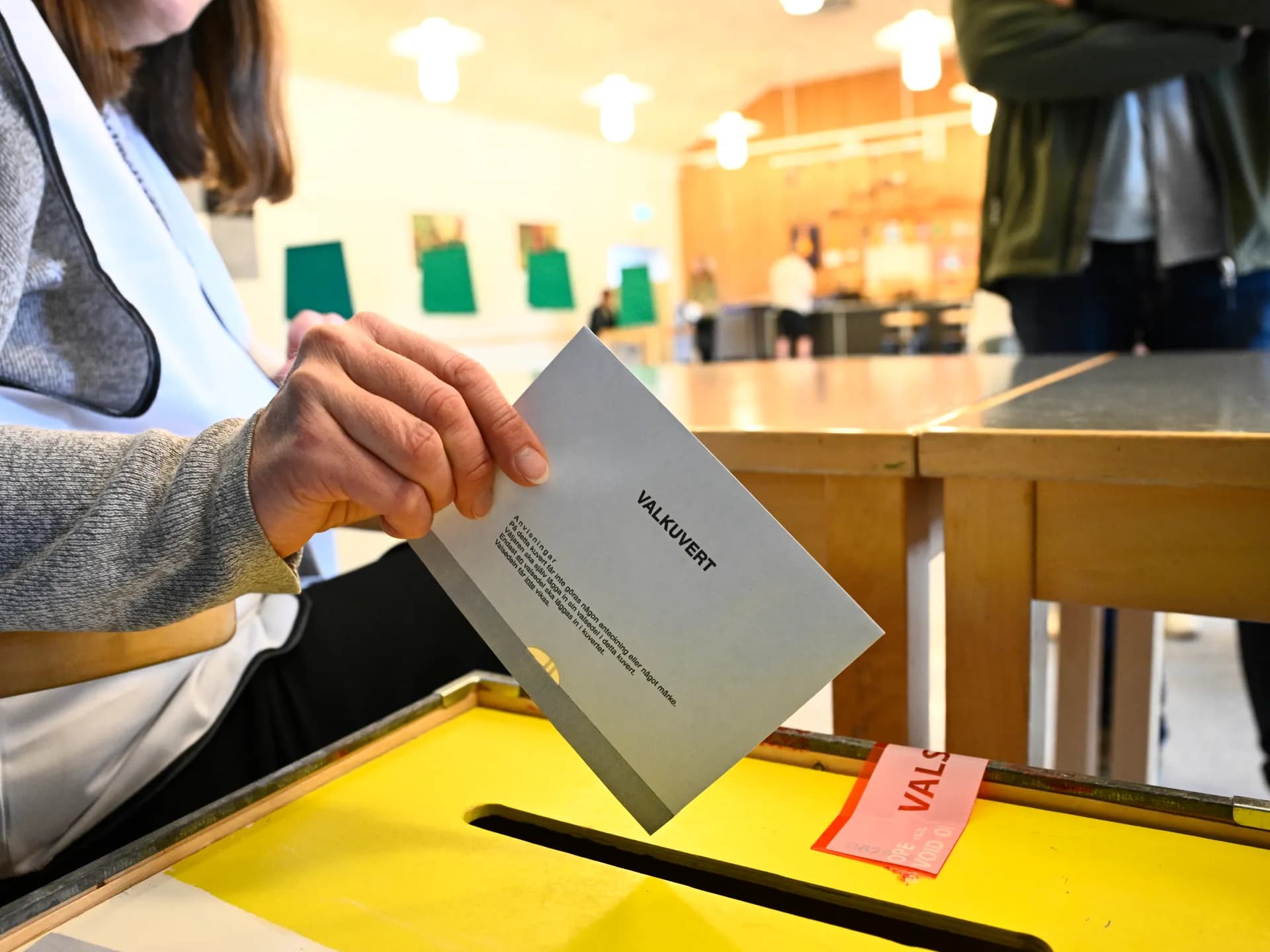Una mano introduce un sobre de votación en una urna en un colegio electoral de Enköping, Suecia