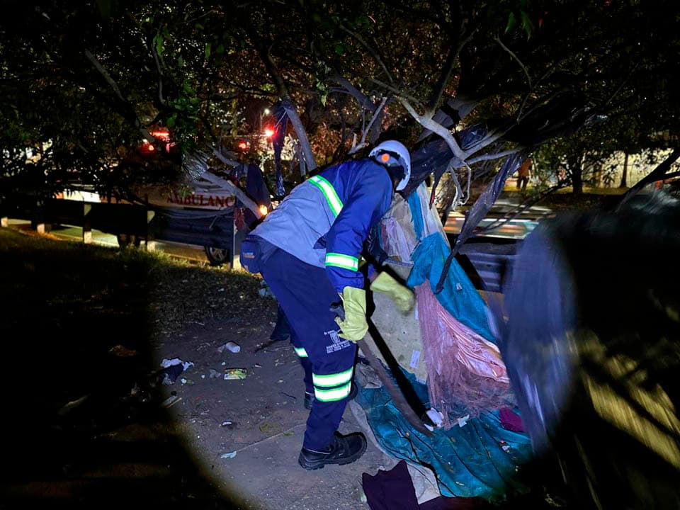 Un funcionario del Distrito retira de noche un cambuche levantado junto a la Avenida Regional, en Medellín