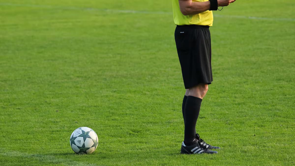 Un árbitro de fútbol de pie junto al balón sobre la cancha (imagen de referencia)