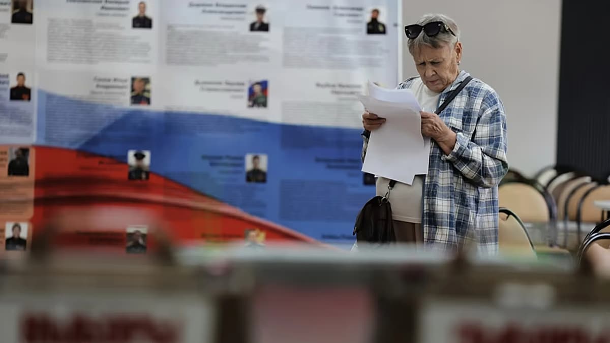 Una mujer lee la papeleta en un centro de votación en Rusia