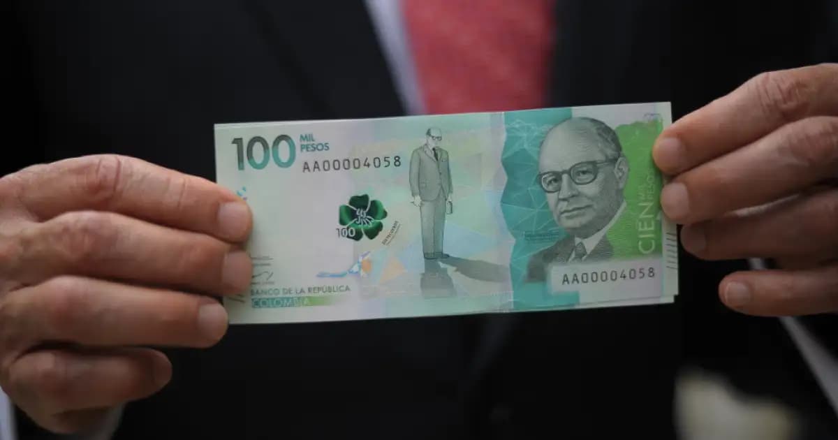 Una persona sostiene un billete de 100.000 pesos colombianos