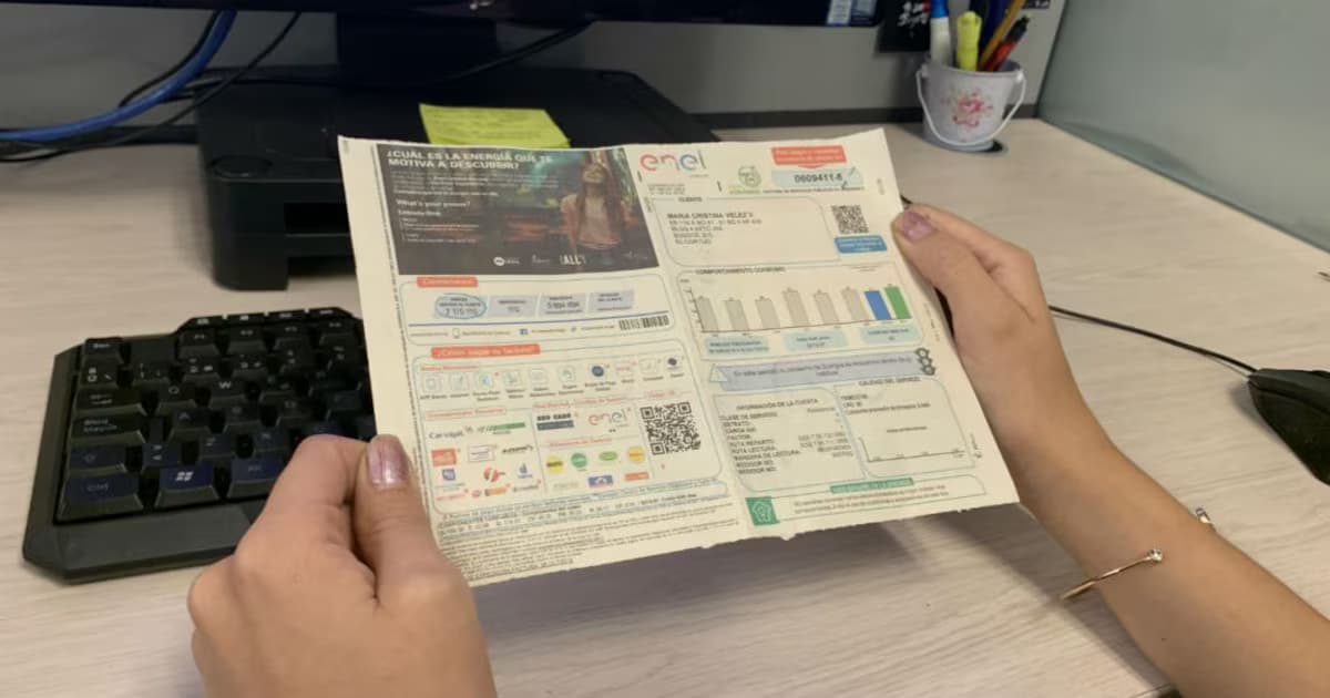 Una mujer sostiene una factura de energía eléctrica sobre un escritorio