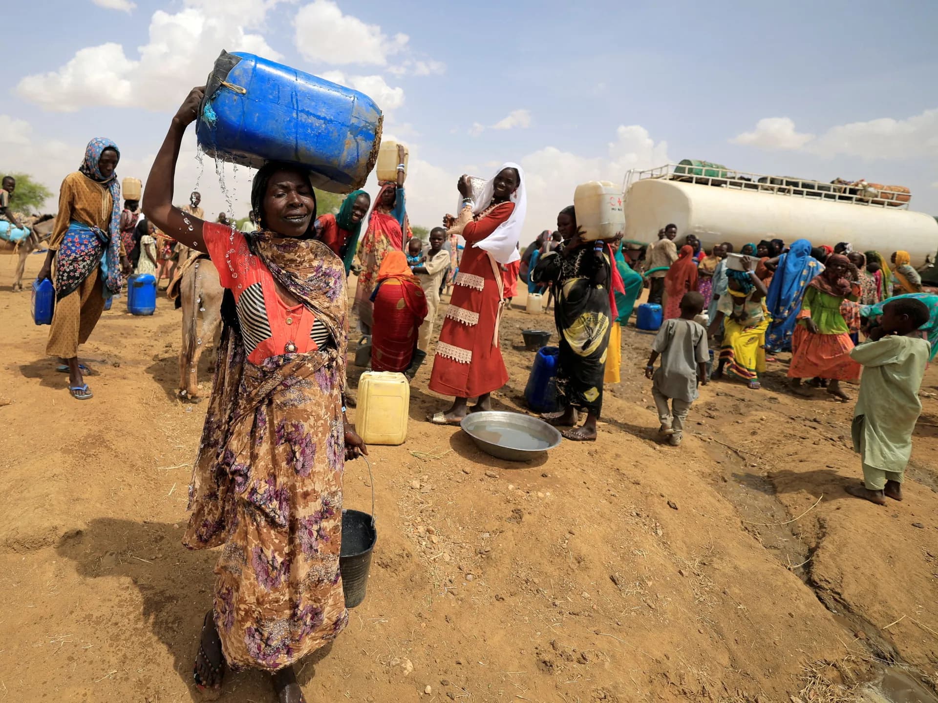 Mujeres sudanesas desplazadas por la guerra cargan agua en un campamento en la frontera con Chad (foto de archivo de 2023)