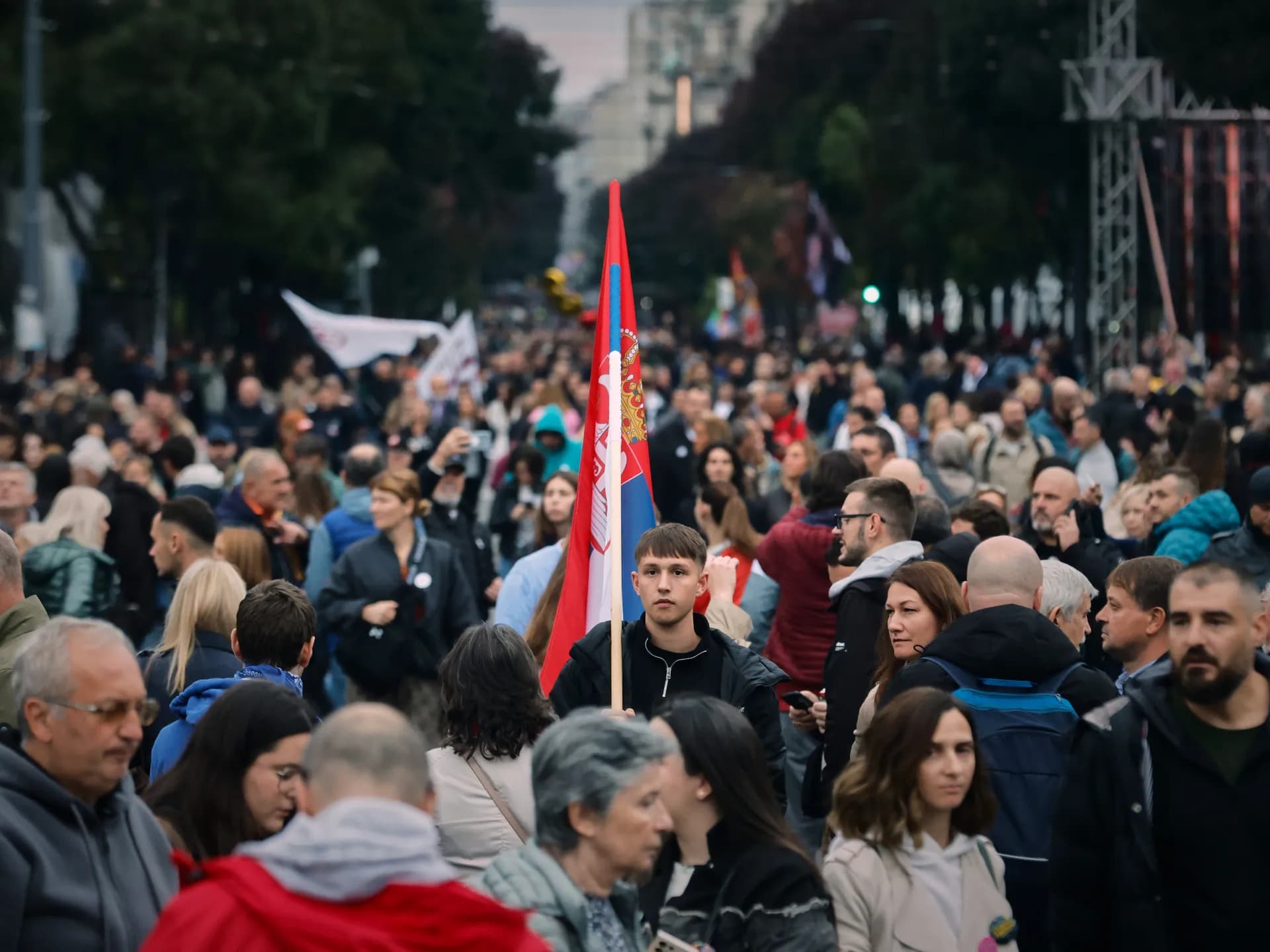 Un joven sostiene una bandera de Serbia en medio de una multitud durante una concentración estudiantil en Belgrado