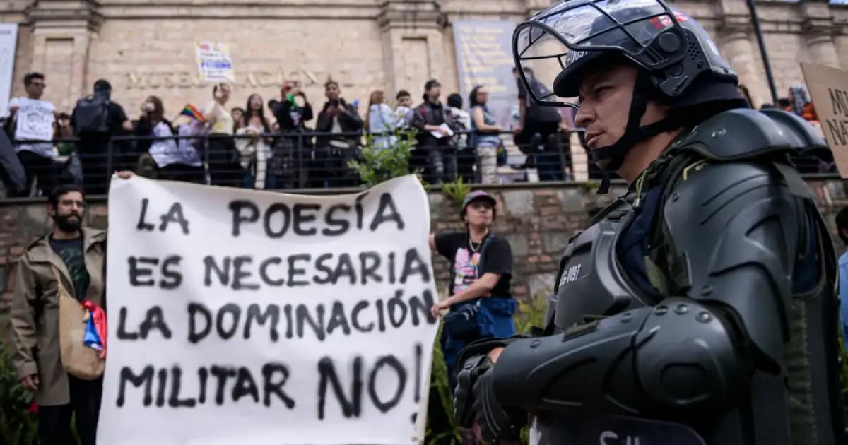 Manifestantes con una pancarta frente a un policía antidisturbios en el plantón ante el Museo Nacional, en Bogotá