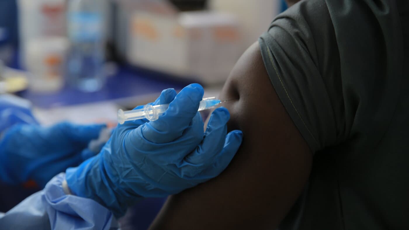 Un trabajador de la salud con guantes azules aplica la vacuna Ervebo contra el ébola en el brazo de una persona en Beni, en el este del Congo