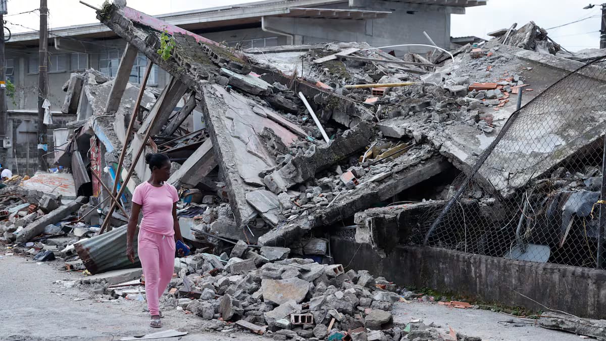 Una mujer camina por una calle junto a las ruinas de varias viviendas derrumbadas por el terremoto