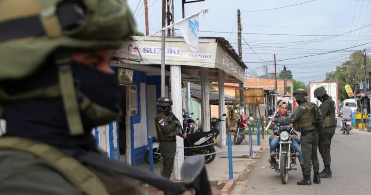 Soldados con casco y chaleco en un puesto de control en la calle de un pueblo detienen a dos hombres en moto