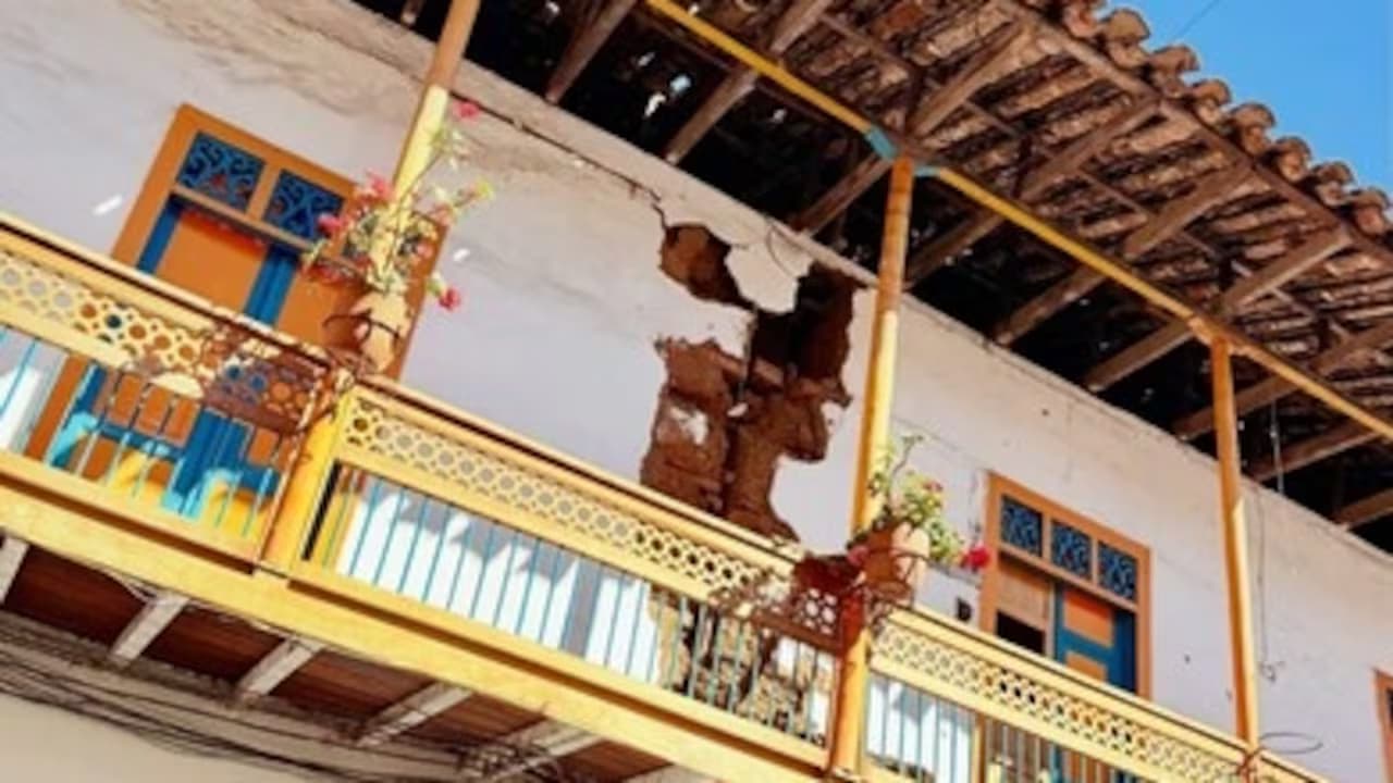 Balcón de una casa colonial con la pared agrietada y el bahareque desprendido bajo el alero de madera
