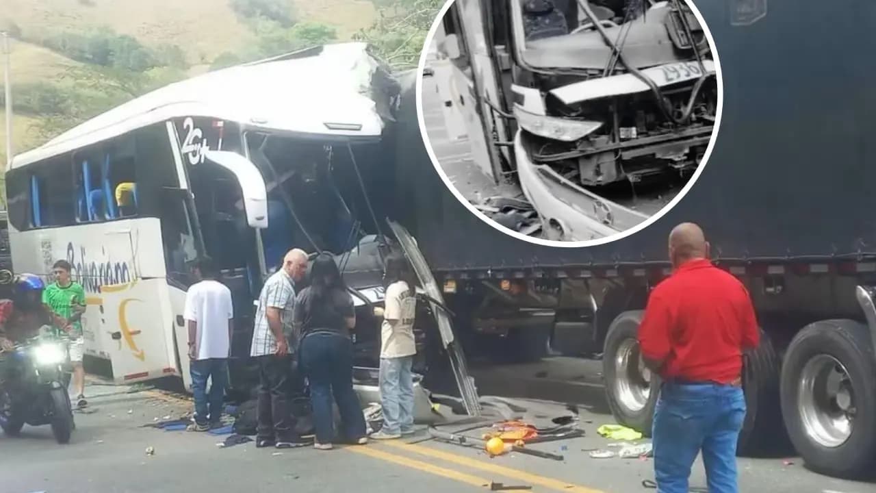 Un bus blanco con el frente destrozado quedó encajado contra la parte trasera de un camión de carga en plena vía; varias personas rodean los vehículos sobre el asfalto sembrado de vidrios