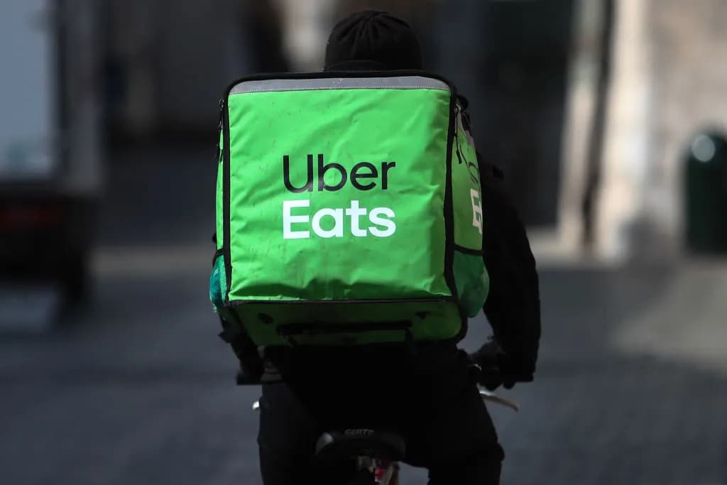 Un repartidor en bicicleta con la mochila verde de Uber Eats