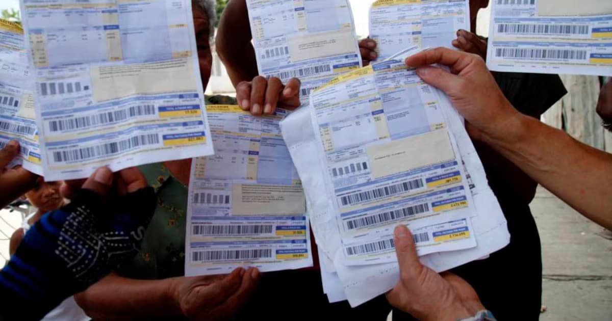 Varias personas sostienen en alto sus facturas de energía