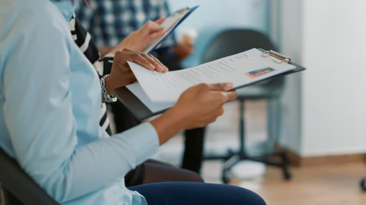 Aspirantes revisan hojas de vida en una sala de espera durante un proceso de contratación