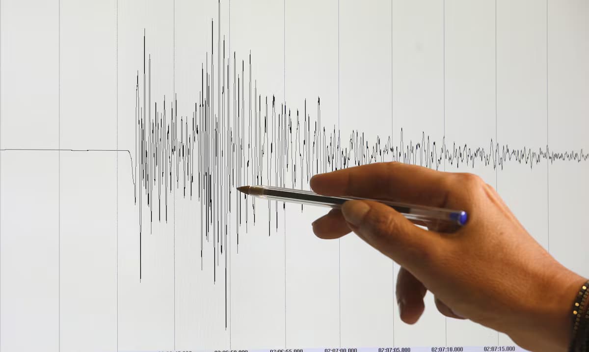Una mano señala con un bolígrafo las ondas de un sismograma en una pantalla, en una fotografía de archivo