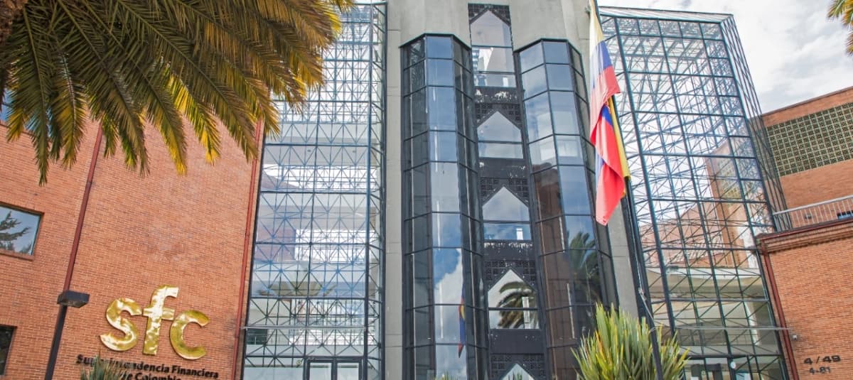 Fachada de vidrio y ladrillo de la sede de la Superintendencia Financiera de Colombia, con la bandera nacional ondeando en el mástil