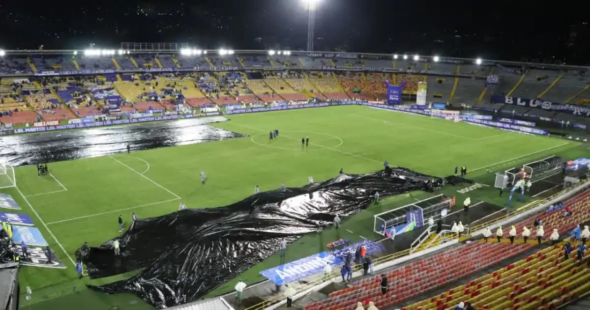 Operarios cubren con plásticos la cancha del estadio El Campín durante una noche de lluvia