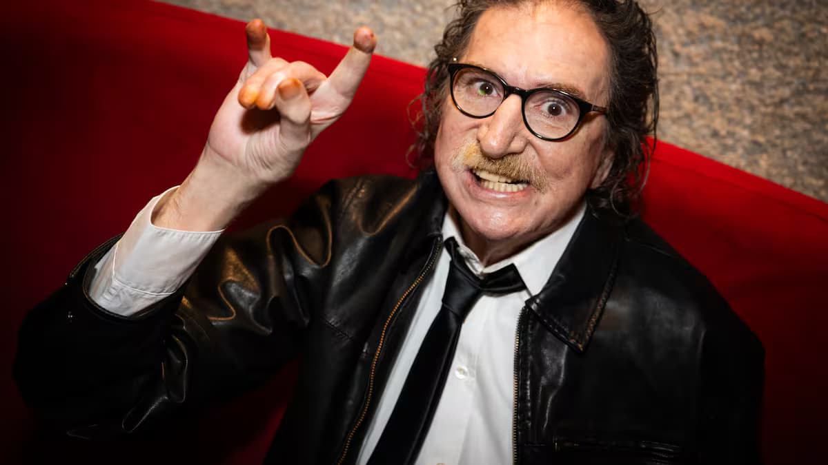 Charly García, con chaqueta de cuero y gafas, hace un gesto con la mano