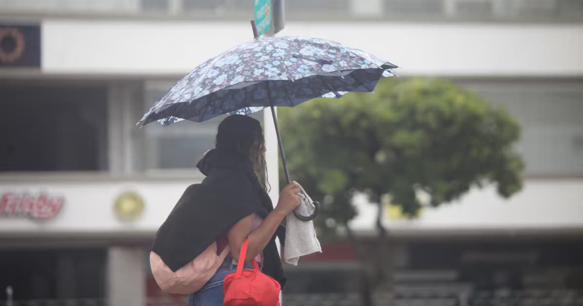 Una mujer se cubre con una sombrilla durante el aguacero en una calle del Caribe colombiano
