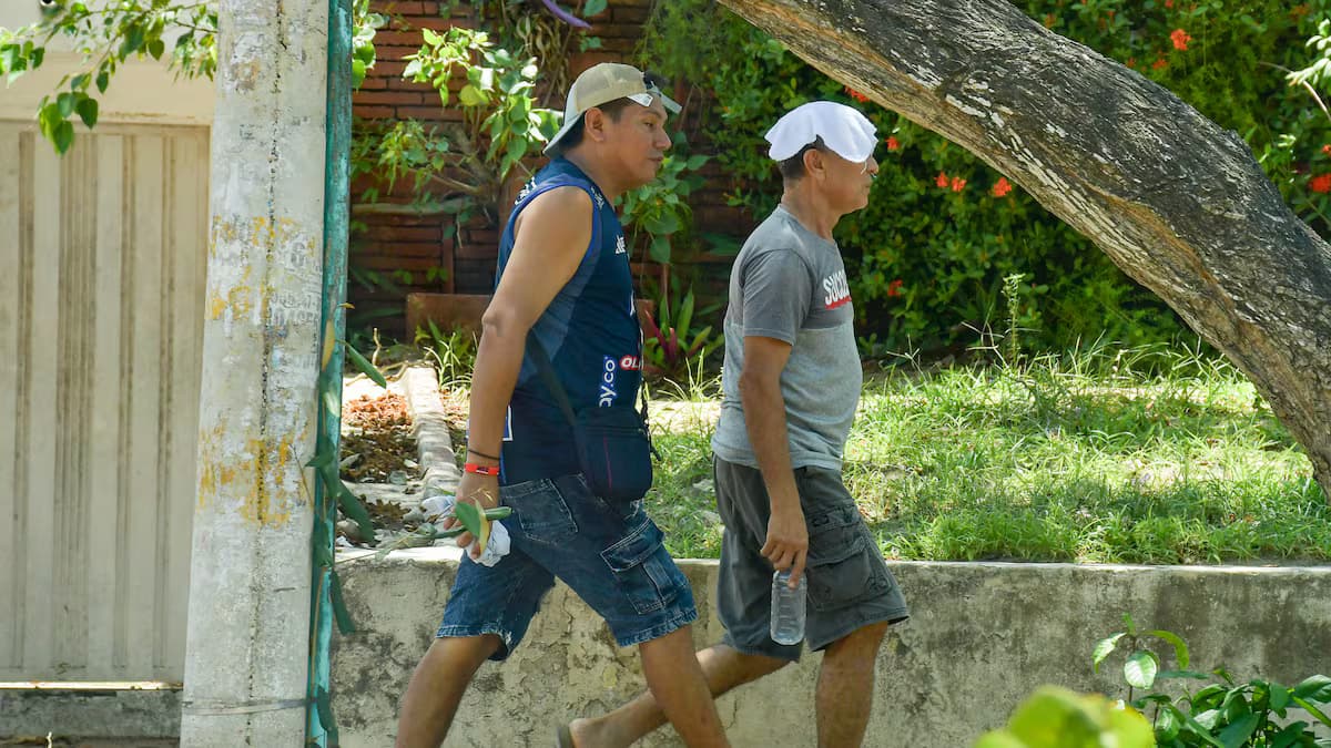 Peatones se protegen del sol con sombrillas en una calle de Barranquilla