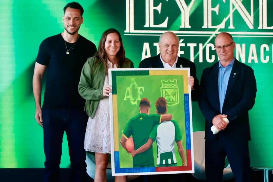 Helio Neto, Carolina Ardila, Antonio José Ardila y el presidente de Chapecoense sostienen una pintura con los escudos de ambos clubes