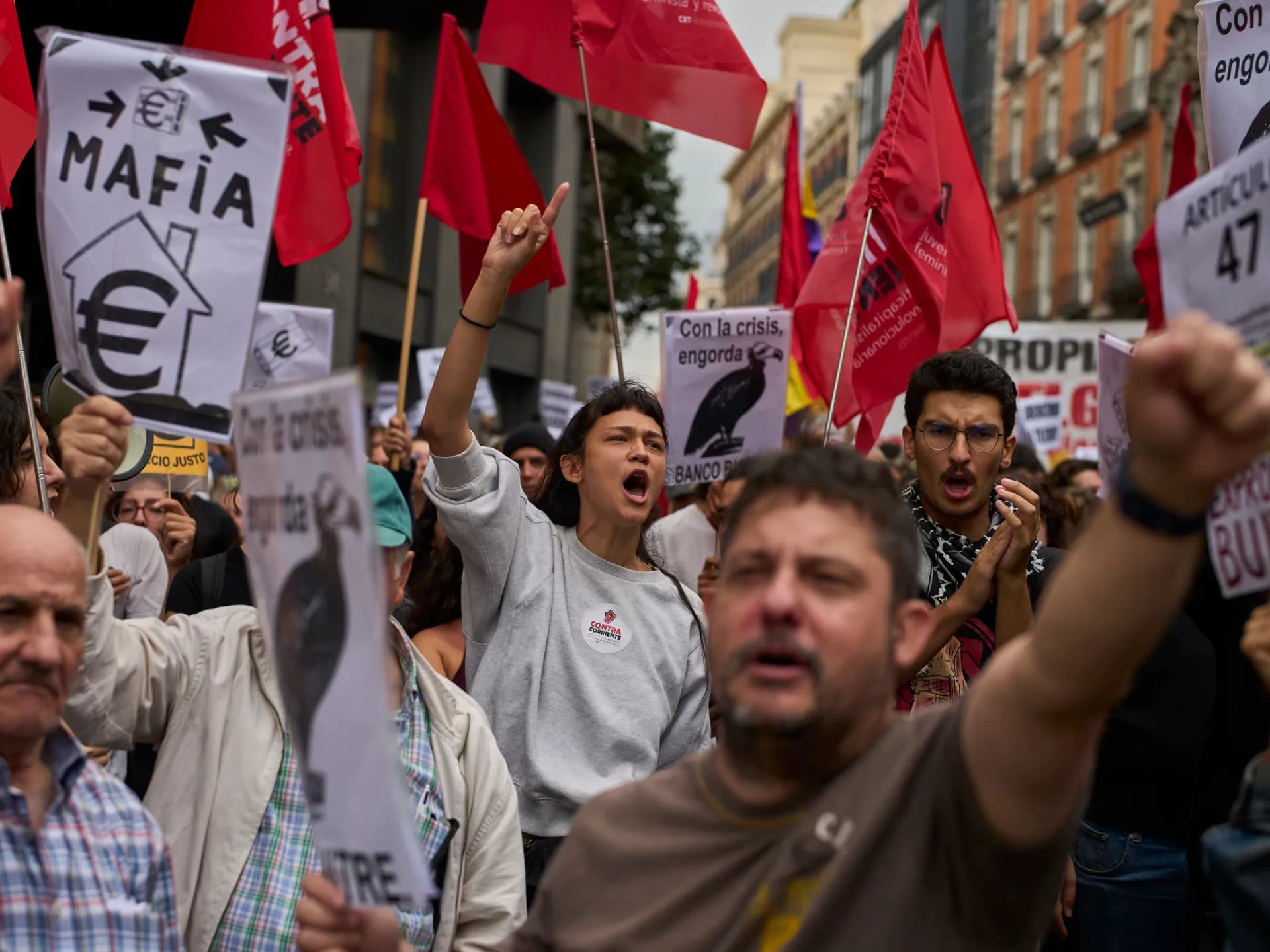 Manifestantes con banderas rojas y carteles contra los fondos buitre protestan en Madrid por el derecho a la vivienda