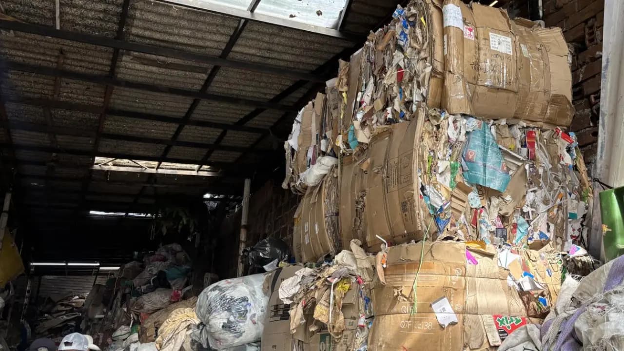 Pacas de cartón y material reciclable apiladas en una bodega de reciclaje