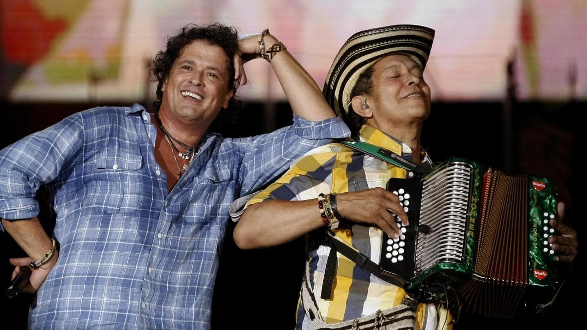 Carlos Vives y Egidio Cuadrado sonríen en el escenario durante un concierto