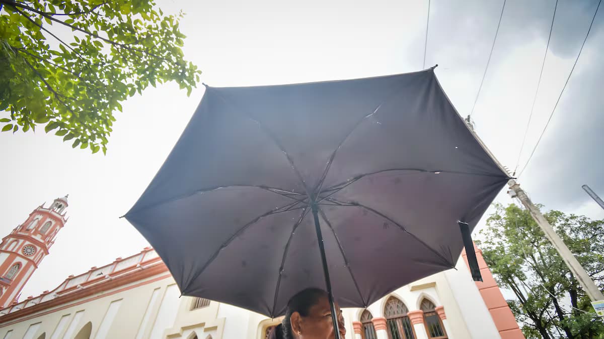 Una mujer se protege del sol con una sombrilla en una calle del Caribe colombiano