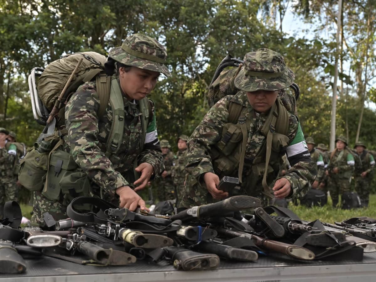 Dos integrantes de la Coordinadora Nacional Ejército Bolivariano ordenan armas sobre una mesa durante una entrega