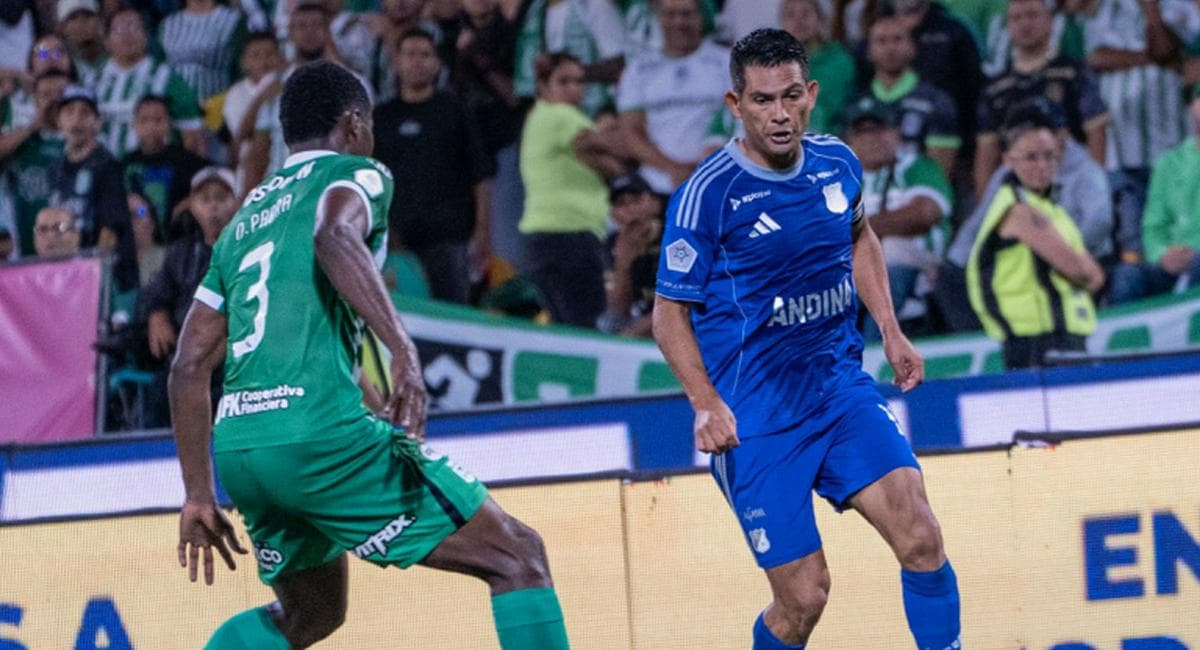 Un jugador de Millonarios conduce el balón ante la marca de un defensor de Nacional en el estadio Atanasio Girardot