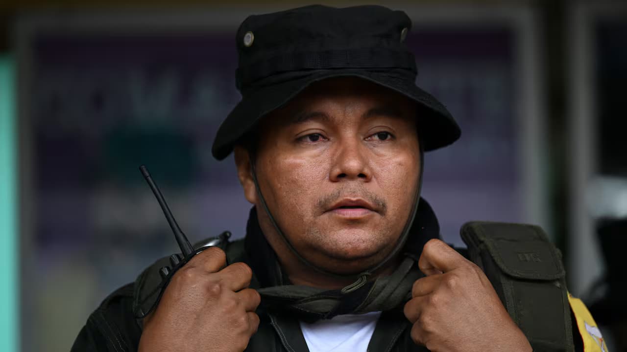 Un hombre armado con sombrero de ala corta y radio de comunicaciones en la mano