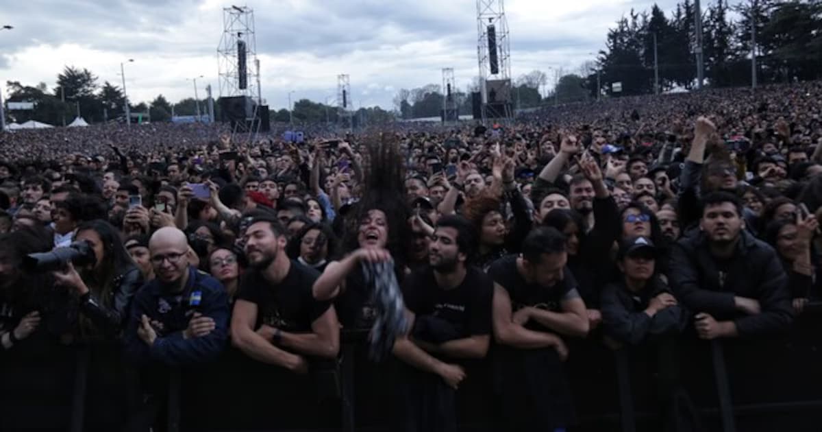 Multitud de asistentes contra la valla frente al escenario de Rock al Parque, con el parque y las torres de sonido al fondo