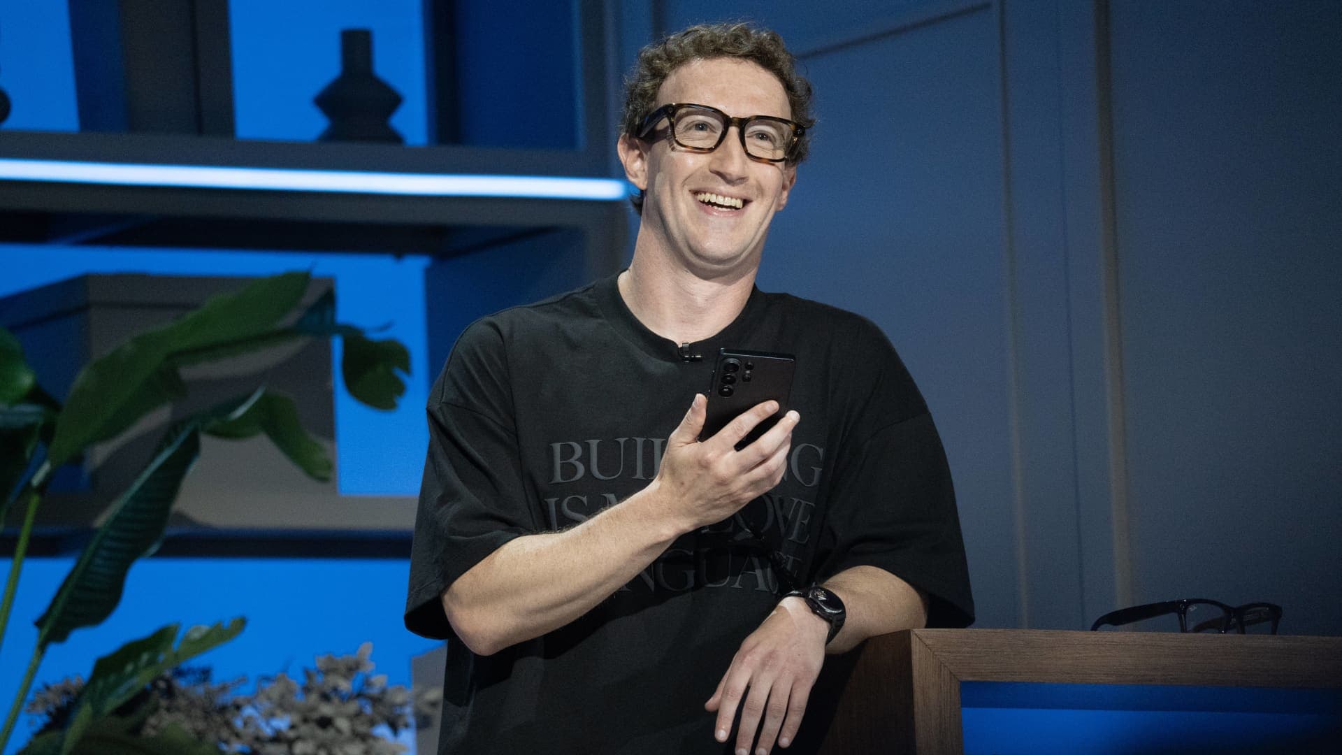 Mark Zuckerberg, director ejecutivo de Meta, sonríe en el escenario de Meta Connect con un teléfono en la mano