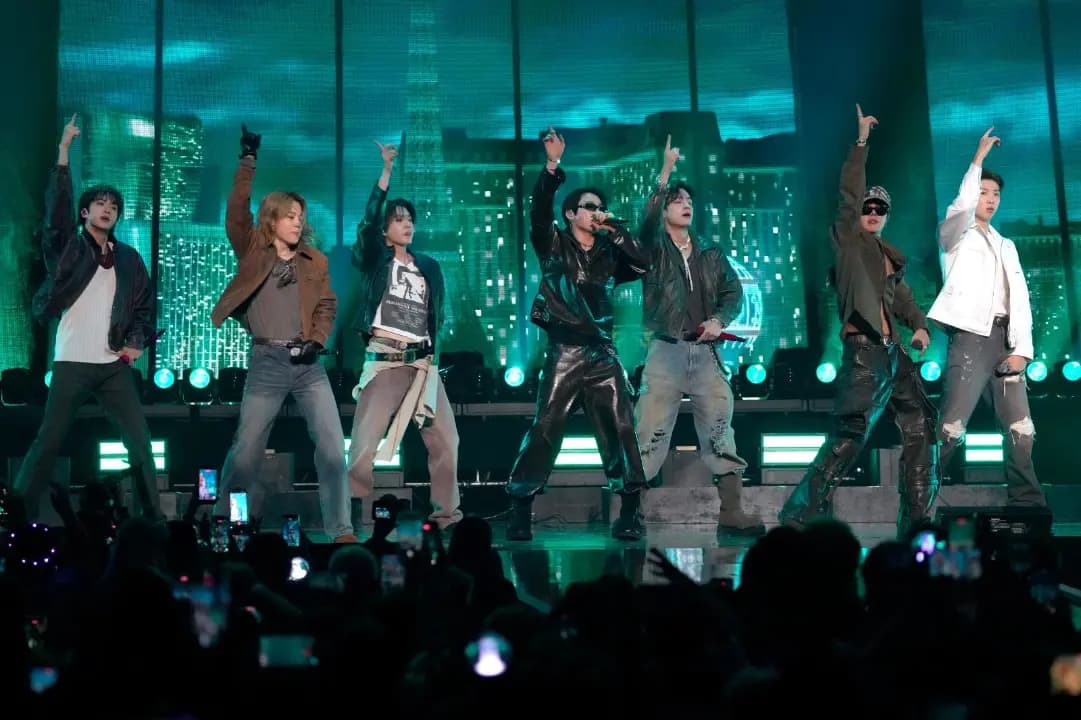 Los siete integrantes de BTS en tarima durante un concierto, con el público en primer plano