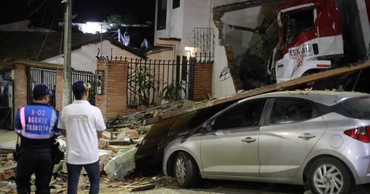Un agente de tránsito y un funcionario de Girón observan el furgón incrustado en una vivienda y un carro cubierto de escombros en el sector Puerta Grande