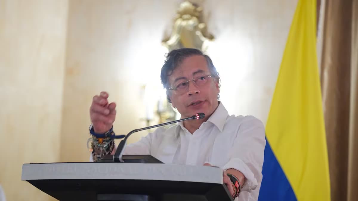 El expresidente Gustavo Petro habla desde un atril junto a una bandera de Colombia