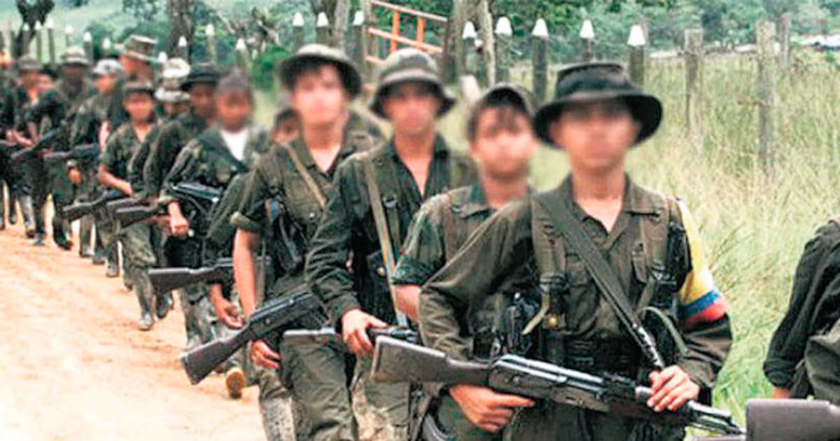 Fila de combatientes de un grupo armado ilegal caminando por un camino rural con los rostros difuminados