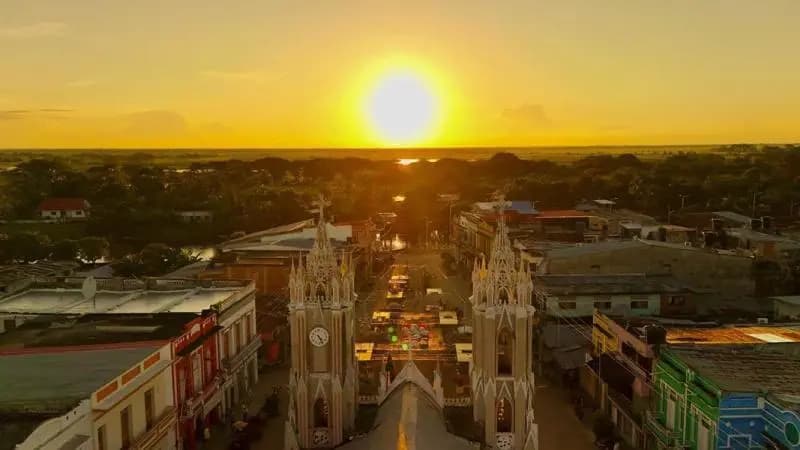Vista aérea del municipio de Sucre al atardecer, con las dos torres de la iglesia en el centro y la ciénaga al fondo