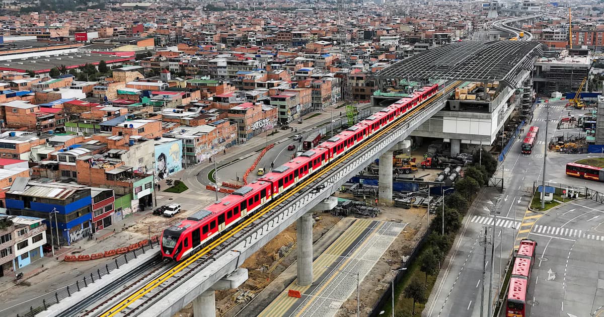 Un tren de la primera línea del metro de Bogotá sobre el viaducto, junto a una estación en construcción