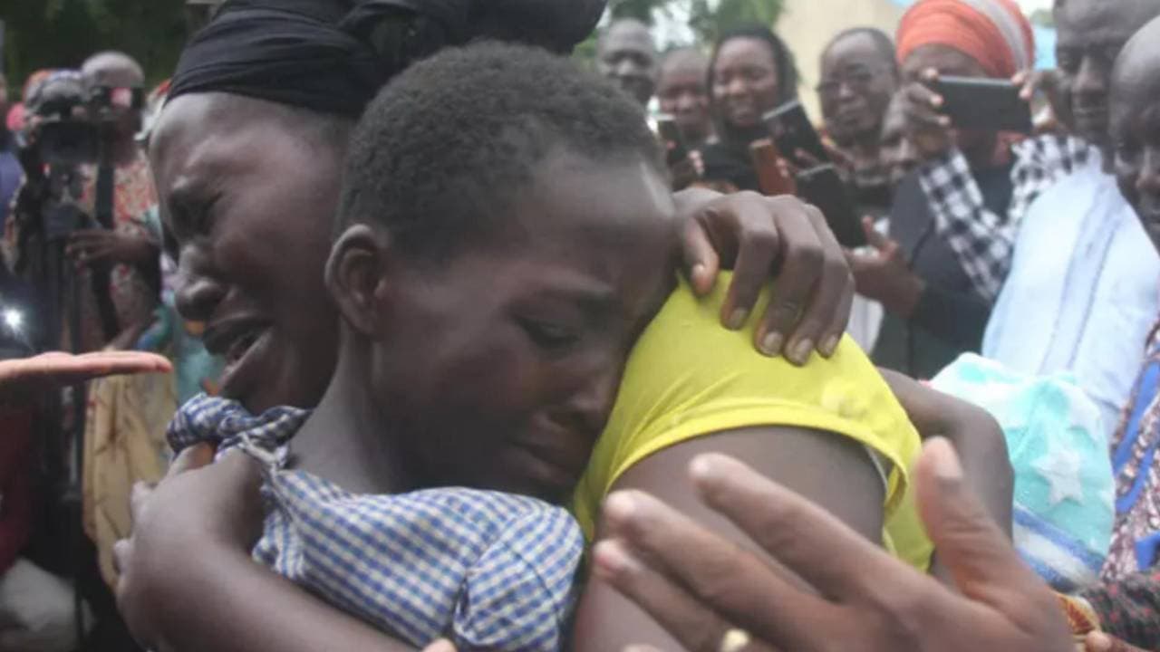 Una mujer llora mientras abraza a un niño en medio de una multitud que registra el reencuentro con teléfonos móviles