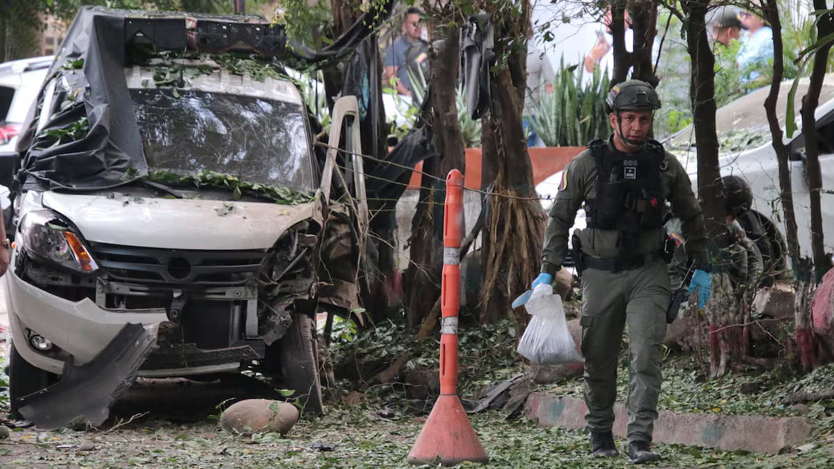 Un técnico antiexplosivos de la Policía camina junto a una camioneta destruida tras la explosión en El Escobal, Cúcuta