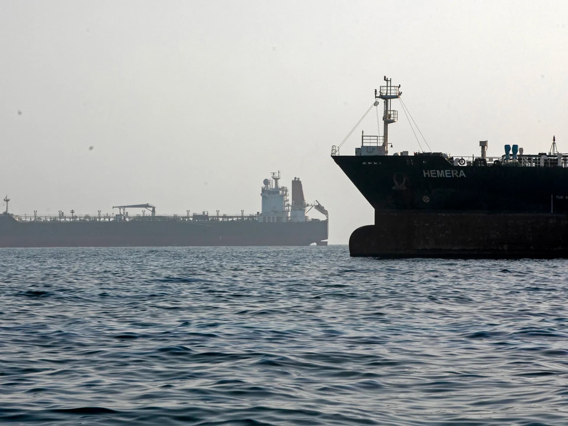 Dos grandes buques petroleros fondeados en aguas tranquilas bajo un cielo brumoso